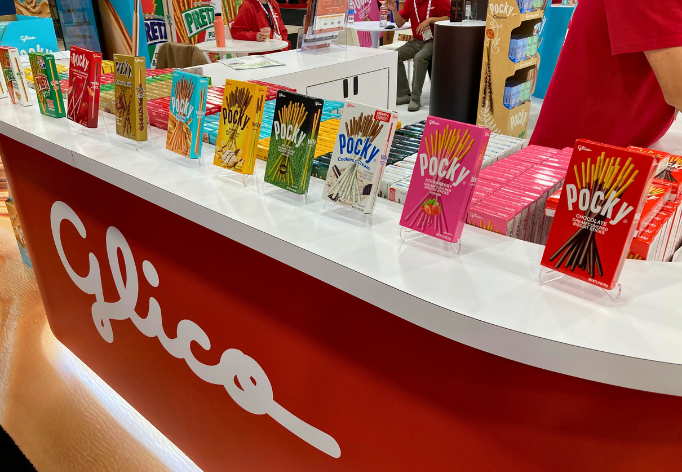 A variety of Pocky boxes on the red Glico counter booth at Sweets & Snacks Expo 2026.